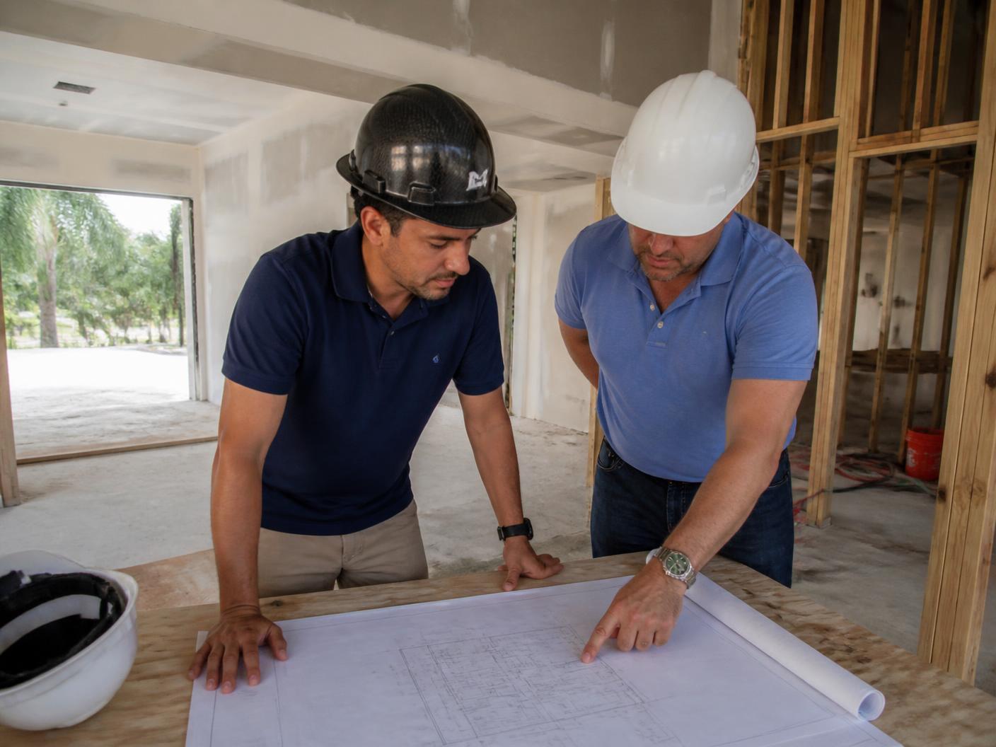 Elite project managers reviewing blueprints inside a Boca Raton home under construction